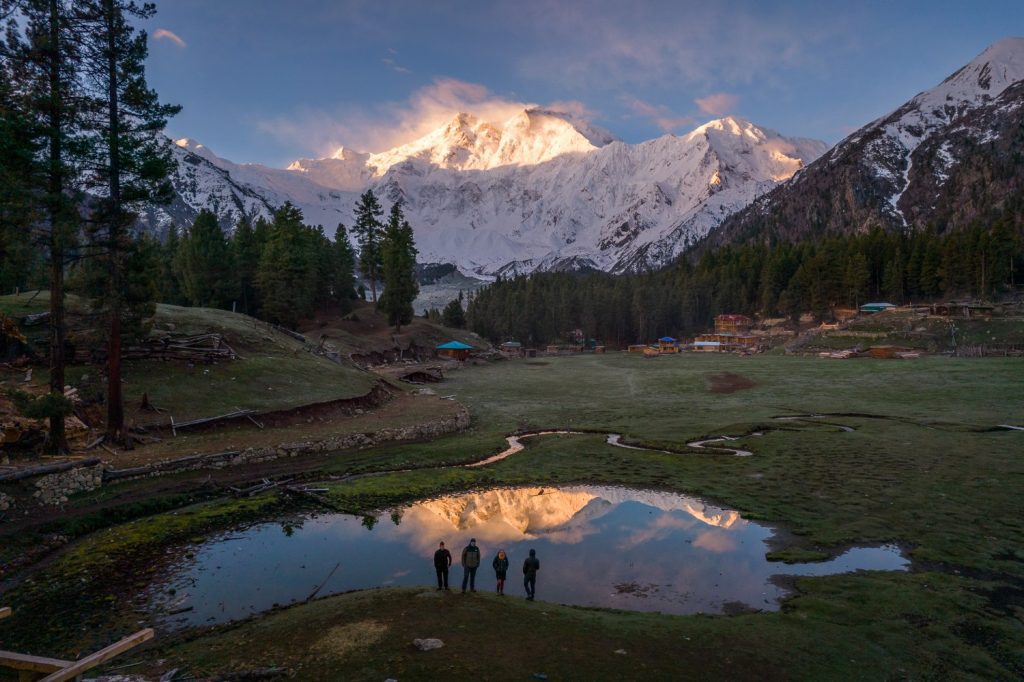 Panoramic view of Fairy Meadows with lush green meadows and the towering Nanga Parbat in the background, showcasing the serene beauty of this trekking destination.